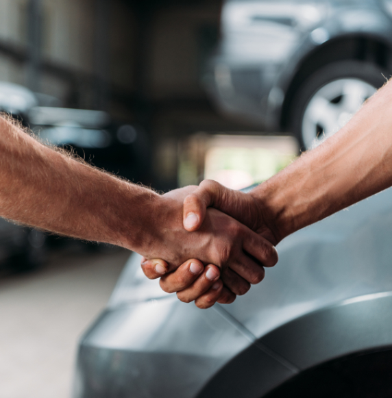 cropped view of mechanics shaking hands in auto repair shop